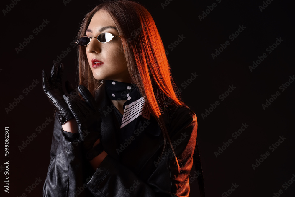 Beautiful young woman in leather gloves and jacket on dark background Beautiful young woman in leather gloves and jacket on dark background