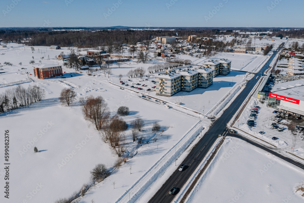 Obraz premium An aerial view of a city during winter, surrounded by built structures and skiing pistes covered in snow from the high angle viewpoint