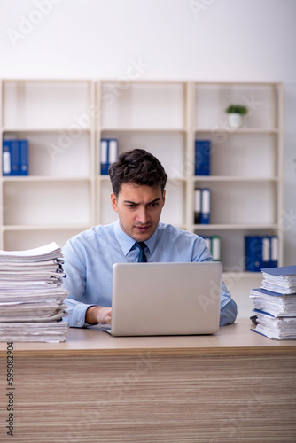 Young male employee and too much work in the office