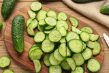 Board with fresh cut cucumbers on wooden background