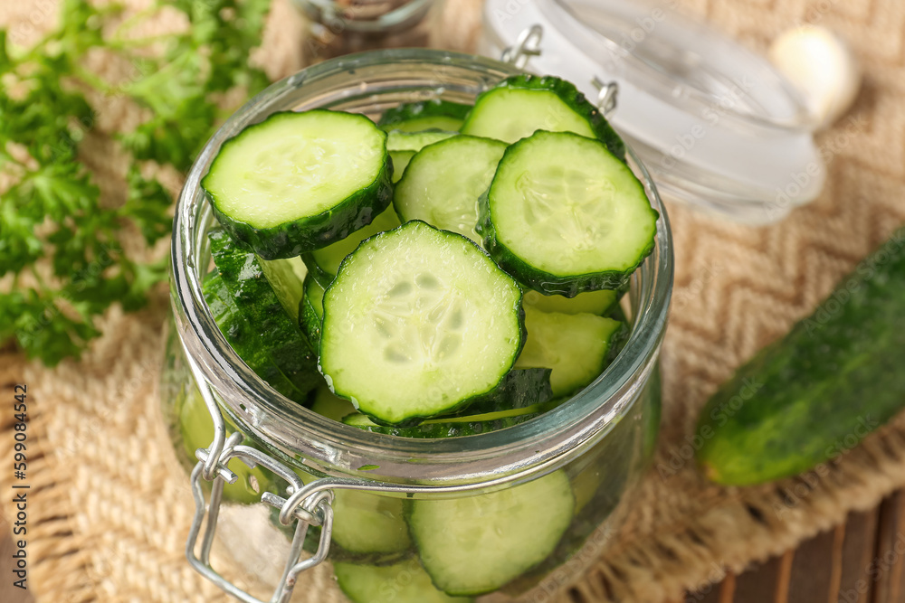 Jar with fresh cut cucumber on table, closeup Jar with fresh cut cucumber on table, closeup