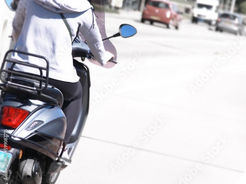 Rückenansicht einer Frau auf Motorroller