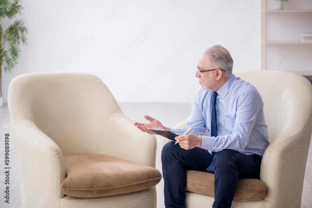 Old male psychologist sitting in the room