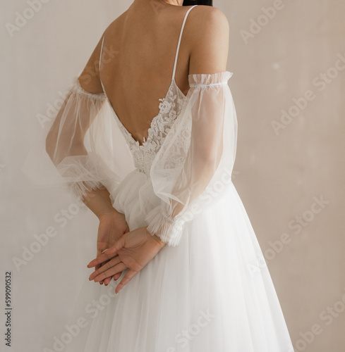 Gorgeous long wedding backless dress. Bride in the shoulderless white wedding dress with fancy sleeves