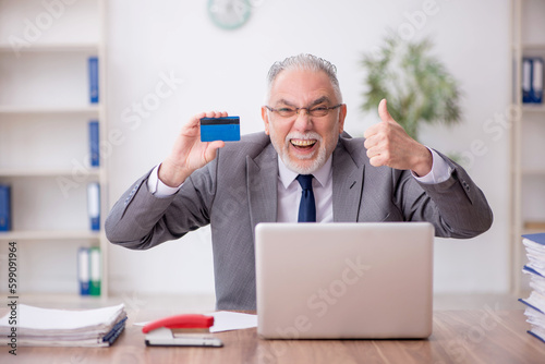 Old male employee holding credit card