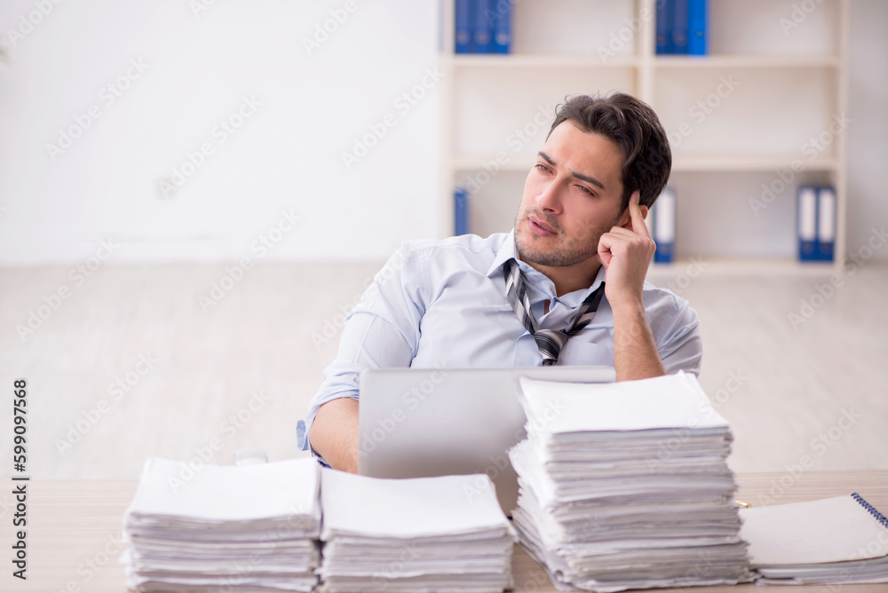 Naklejka premium Young male employee and too much work in the office