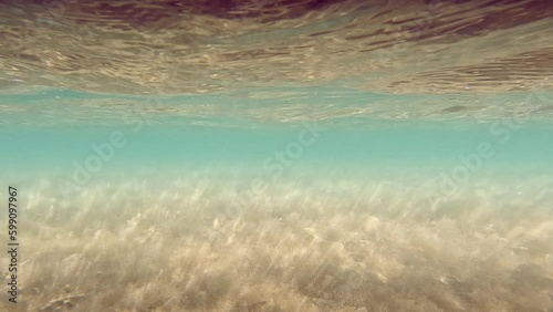 Underwater sandy sea bottom. Water Waves Mixing the sand. Stretch of sand. Rays of sun shining trought the ocean. Caustic Abstract background. Turquoise sea color. Slow motion Seamless loop. 