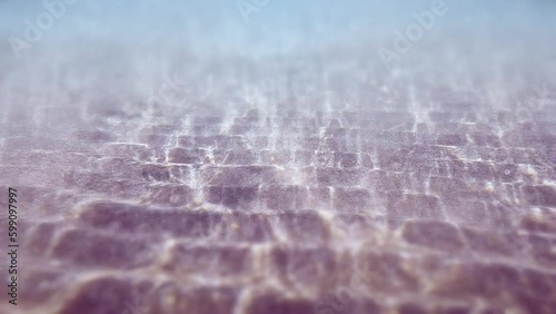 Underwater sandy sea bottom. Water Waves Mixing the sand. Stretch of sand. Rays of sun shining trought the ocean. Caustic Abstract background. Slow motion Seamless loop. 