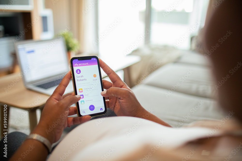 Young pregnant latina woman using a banking app on the couch in the living room Young pregnant latina woman using a banking app on the couch in the living room