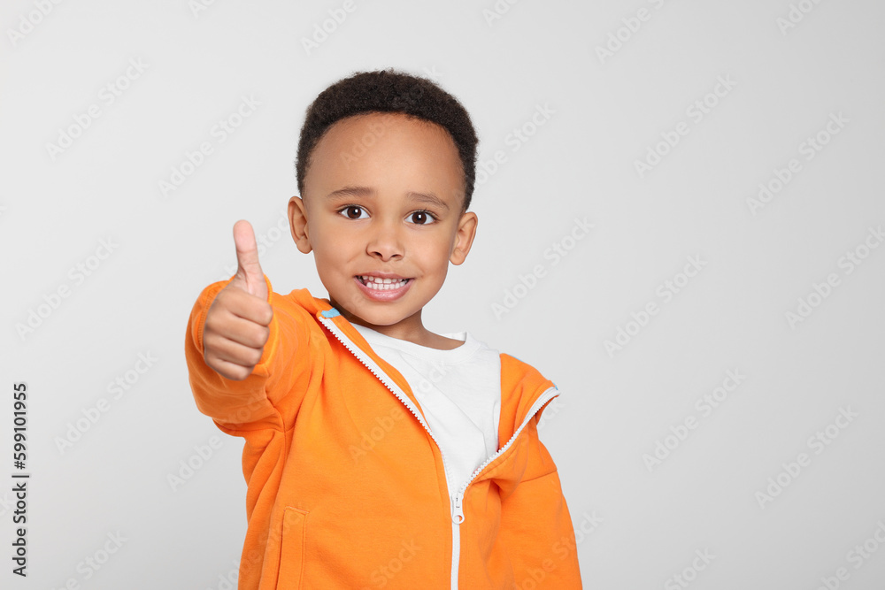 African-American boy showing thumb up on light grey background African-American boy showing thumb up on light grey background