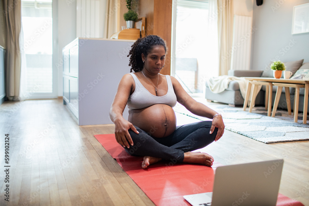 Young pregnant latina woman meditating at home wihle using a laptop Young pregnant latina woman meditating at home wihle using a laptop