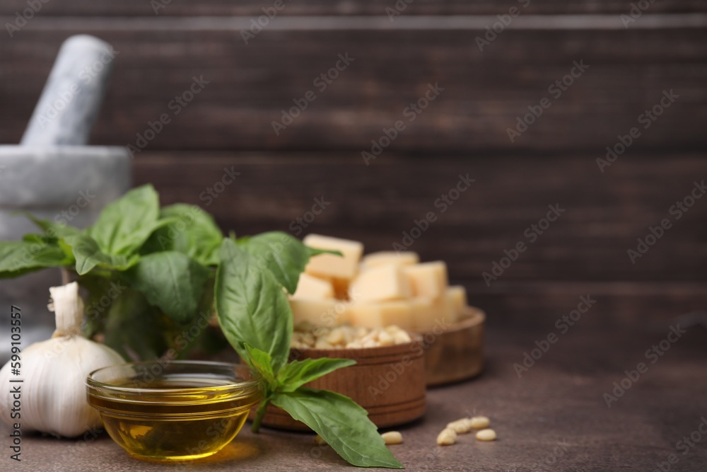 Different ingredients for cooking tasty pesto sauce on brown textured table, closeup. Space for text