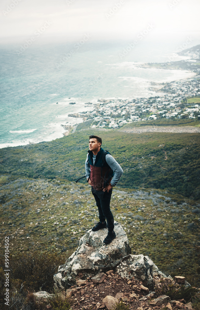 Obraz premium If you think youve peaked, find a new mountain. a young man standing on a cliff while out on a hike.