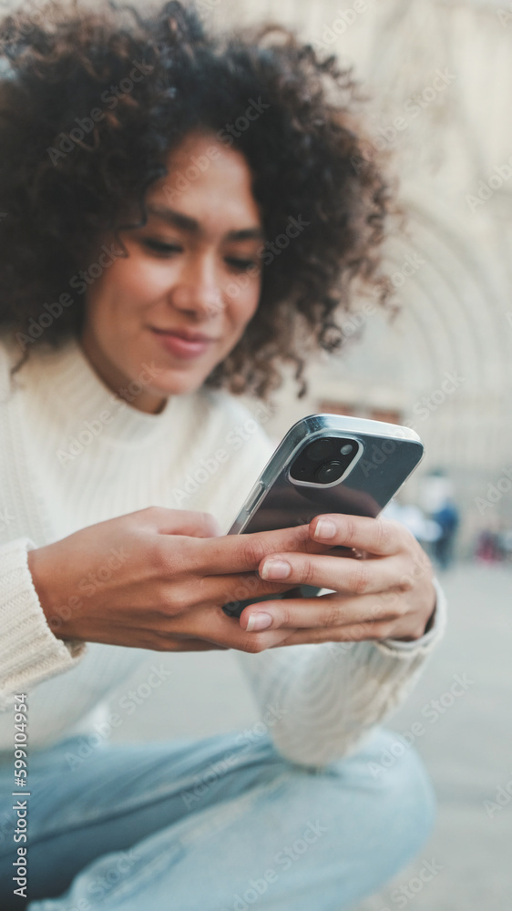 Close up, young woman scrolls on a cell phone. Happy girl uses mobile phone on old city background Close up, young woman scrolls on a cell phone. Happy girl uses mobile phone on old city background