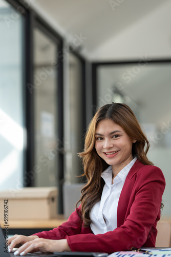 Beautiful Asian businesswoman working on laptop and taking financial details from statistical graphs, charts. Successful business results in modern office with joy. Free Download Beautiful Asian businesswoman working on laptop and taking financial details from statistical graphs, charts. Successful business results in modern office with joy. - GFXLoad
