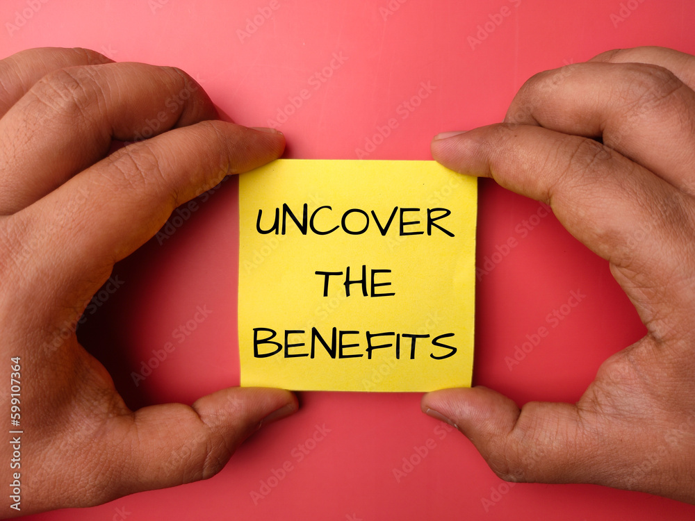 Hand holding note paper with the word UNCOVER THE BENEFIT Hand holding note paper with the word UNCOVER THE BENEFIT