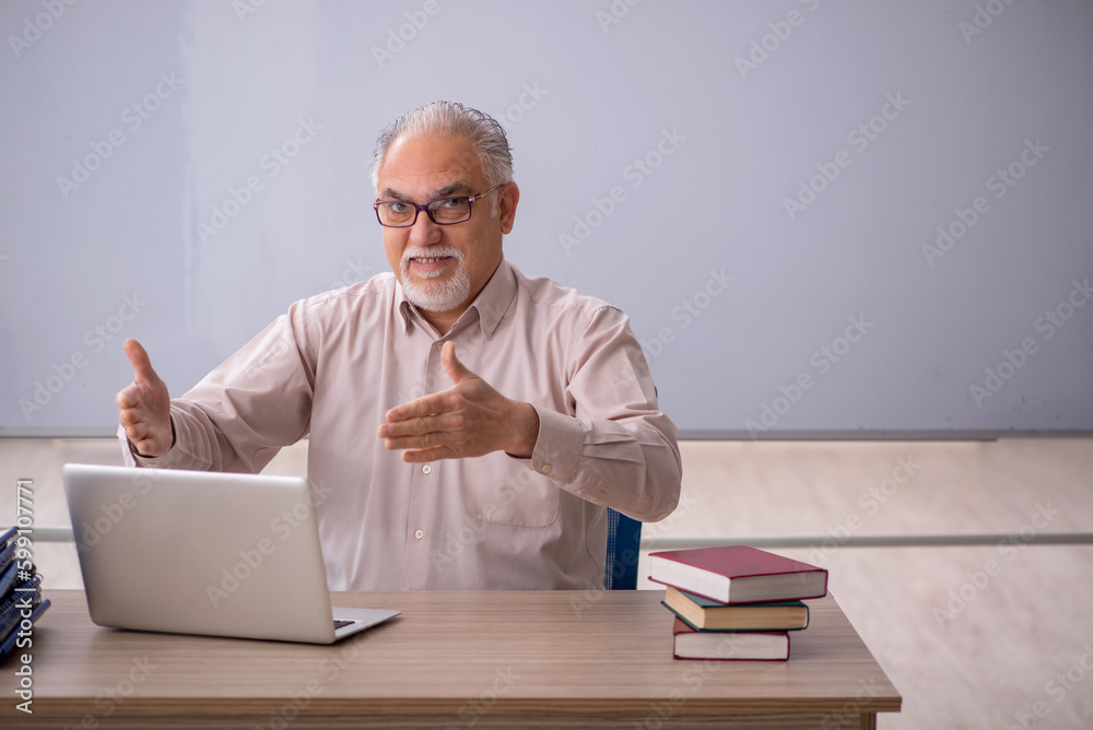 Old male teacher in front of whiteboard