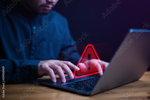 Businessman or it staffs, programmer, developer using computer laptop with triangle caution warning sign for notification error and maintenance concept. Hack system alert, warning computer system