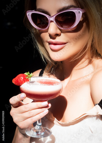 Young beautiful woman hold fresh cold beverage in restaurant. Sexy lady drink cocktait. Sensual girl Female enjoys a summer drink. Alcoholic drinks. photo