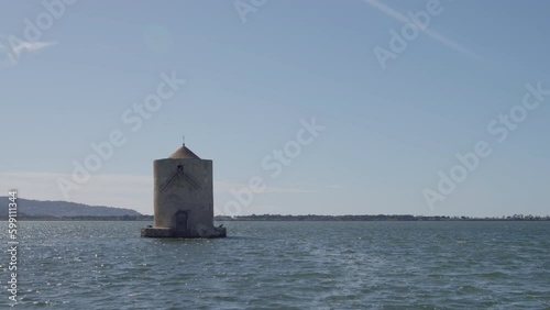 Old lighthouse stands in solitude in ocean on sunny day, Tuscany, Maremma, italy photo