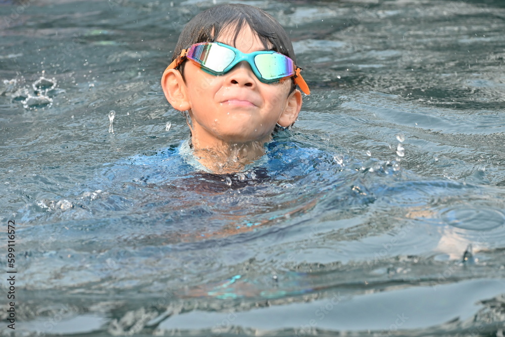 happy little boy swimming in the pool on summertime