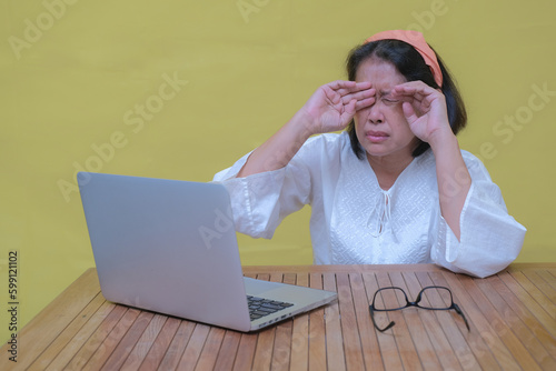 A middle-aged woman took off her glasses and rubbed her eyes; tired expression photo