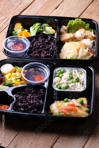 healthy food bento with black rice, dori fish fillet, vegetable soup, shredded chicken, and fruit jelly. For diet weight loss program. healthy lunch menu in a plastic container. catering menu diet.  © Ika