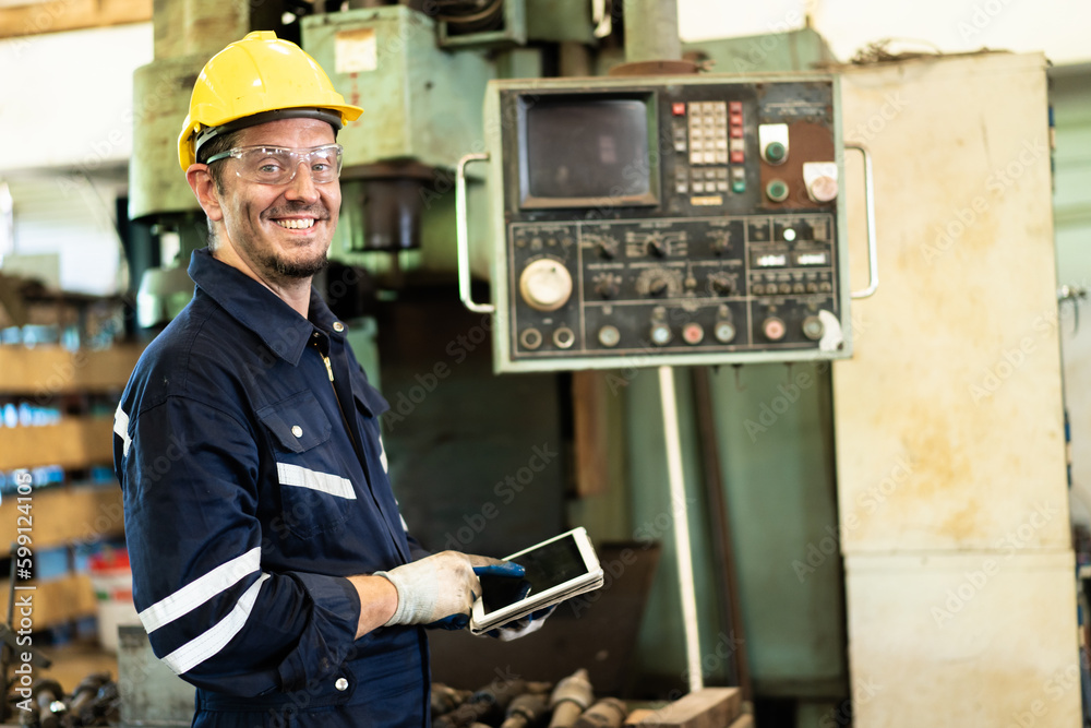 Professional caucasian white ethnicity male technician operating the heavy duty machine in the lathing factory. Technician in safety and helmet suit controlling a machine in factory. Professional caucasian white ethnicity male technician operating the heavy duty machine in the lathing factory. Technician in safety and helmet suit controlling a machine in factory.