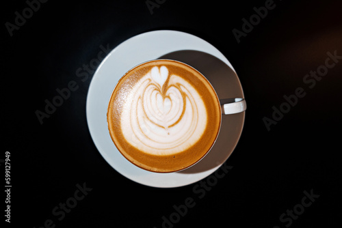 Cup of coffee latte with heart shape on black background