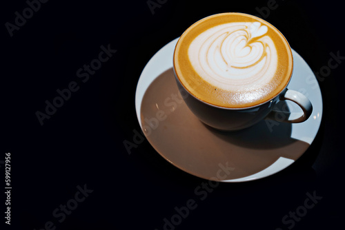 Cup of coffee latte with heart shape on black background