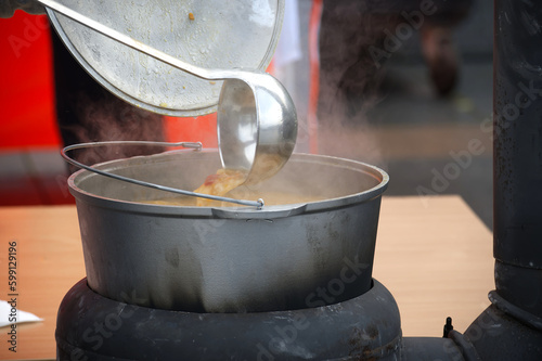 Outdoor preparing soup in a cast iron boiler