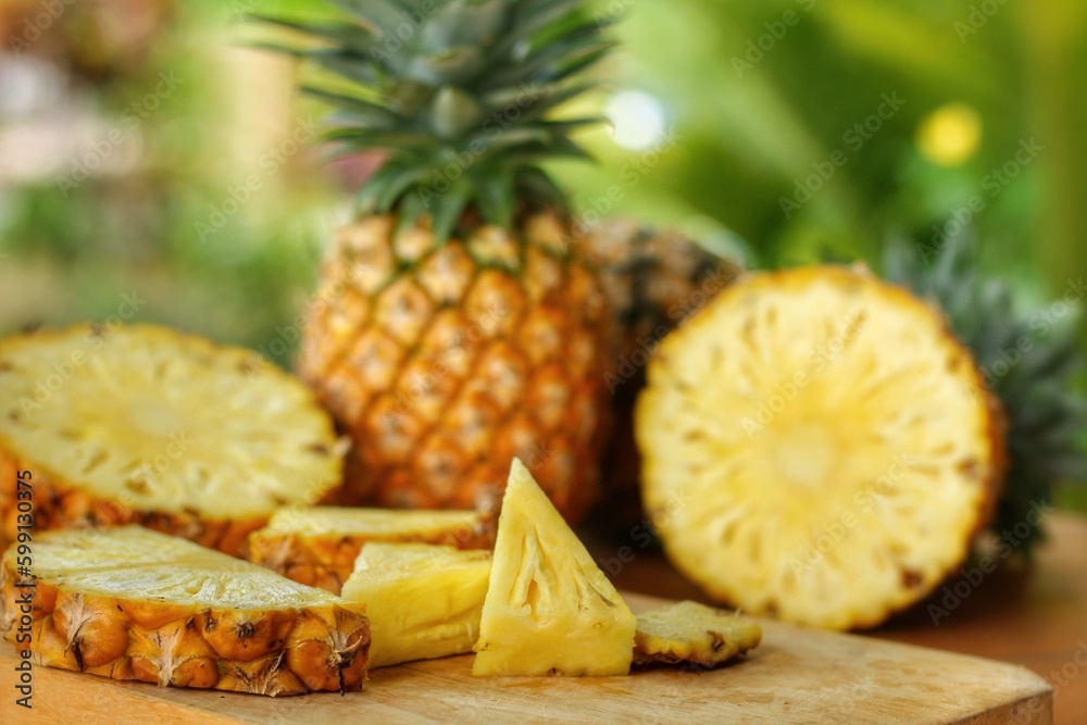 Sliced and half of Pineapple(Ananas comosus) on wooden table with blurred garden background.Sweet,sour and juicy taste.Have a lot of fiber,vitamins C and minerals.Fruits or healthcare concept. Sliced and half of Pineapple(Ananas comosus) on wooden table with blurred garden background.Sweet,sour and juicy taste.Have a lot of fiber,vitamins C and minerals.Fruits or healthcare concept.