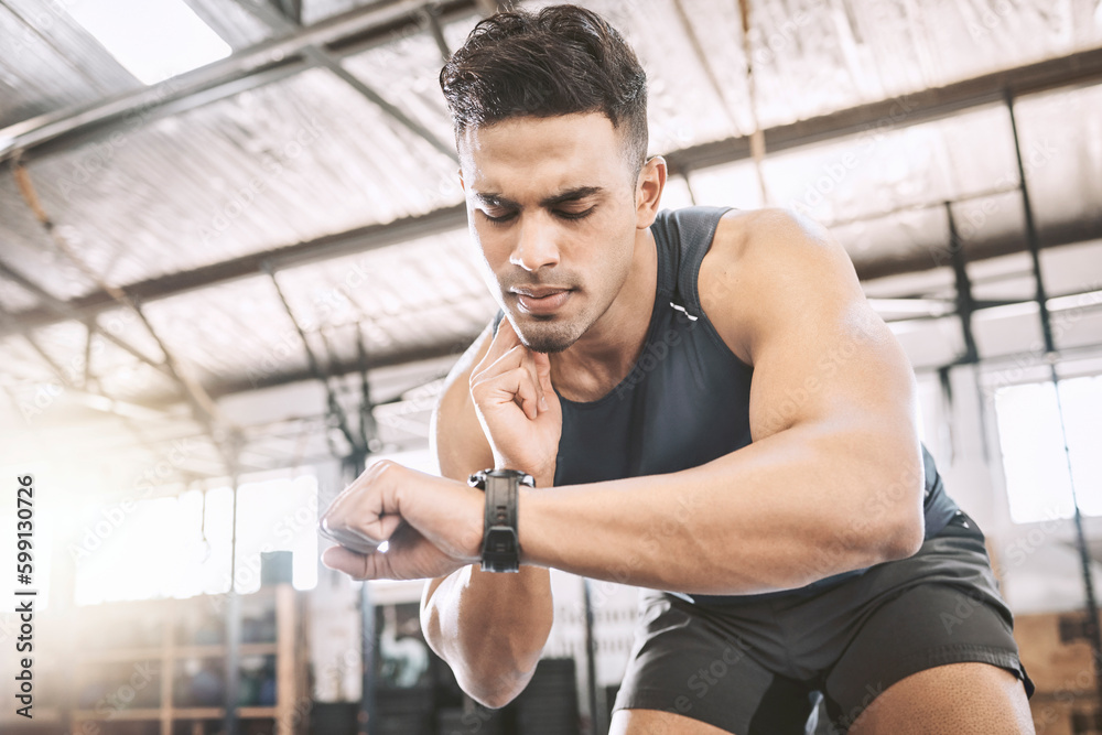 Fit trainer checking his pulse after a workout. Young athlete timing his progress on a watch after exercise. Bodybuilder tracking his heartbeat during a training exercise. Sporty man in the gym Fit trainer checking his pulse after a workout. Young athlete timing his progress on a watch after exercise. Bodybuilder tracking his heartbeat during a training exercise. Sporty man in the gym