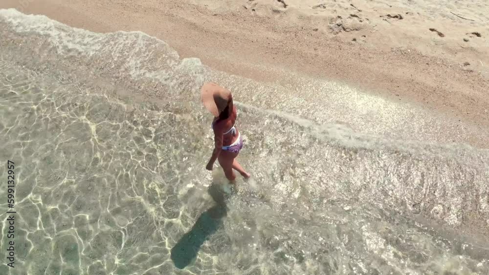 Aerial view of a beautiful woman who is walking along empty beach in the turquoise sea. Top view from drone. Aerial view of a beautiful woman who is walking along empty beach in the turquoise sea. Top view from drone.