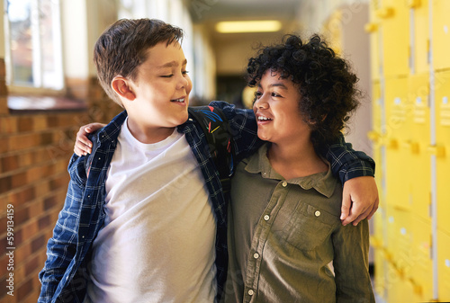 Were best friends. two young boys standing in the hallway at school with their arms around each other.