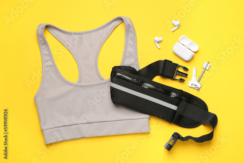 Flat lay composition with stylish black waist bag on yellow background