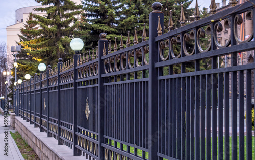 A long iron fence with sharp spikes. Cast-iron fence.