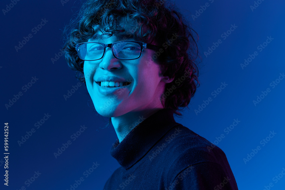 Man in black sweater model poses in glasses smile, hipster lifestyle, portrait blue background, mixed neon light, fashion style and trends boys teenager, copy space Man in black sweater model poses in glasses smile, hipster lifestyle, portrait blue background, mixed neon light, fashion style and trends boys teenager, copy space