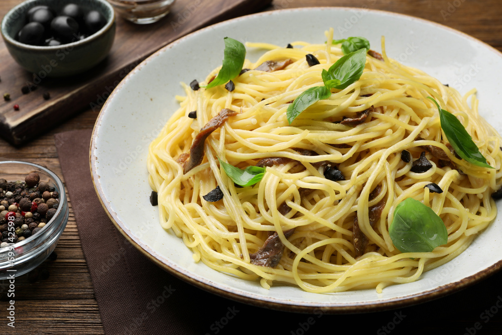 Delicious pasta with anchovies, olives and basil on wooden table, closeup Delicious pasta with anchovies, olives and basil on wooden table, closeup