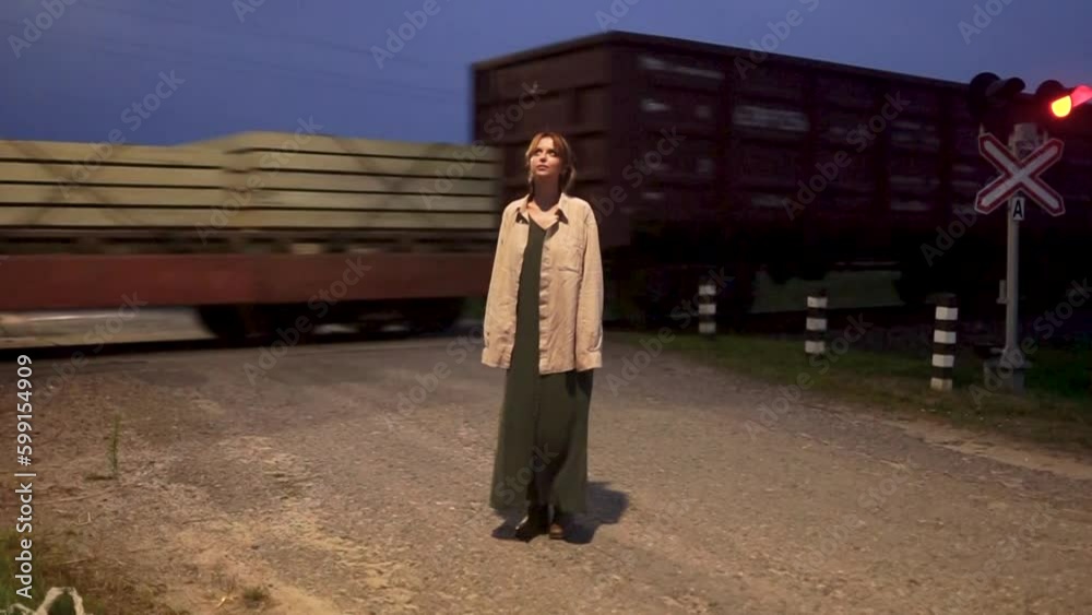 A woman stands next to a passing train on a summer evening A woman stands next to a passing train on a summer evening