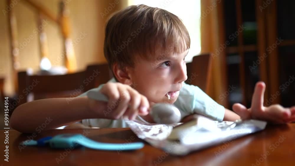 boy child eating ice cream at the table during the day