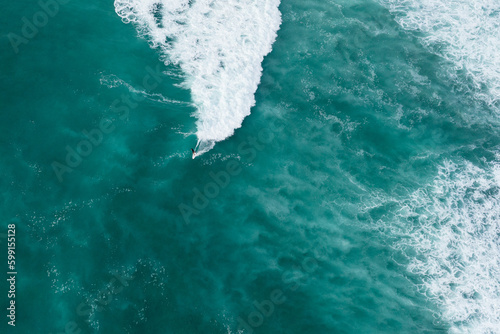 Drone shot of a surfer riding wave in Hawaii