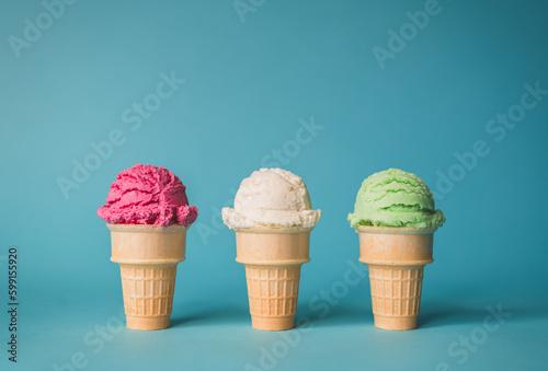 фотографія Three ice cream cones in a variety of flavours on blue background