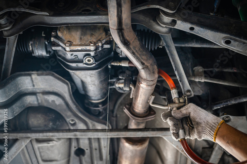 Auto mechanic filling rear differential fluid ,rear differential oil change service.