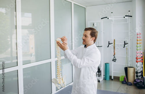 a vertebrologist holds a model of the spine in his hand.