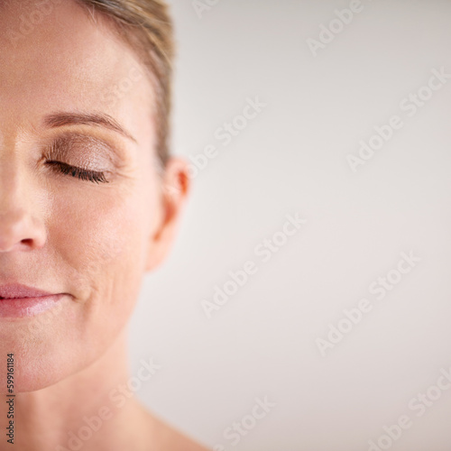 Beauty, mockup and half face with a woman in studio on a gray background for cosmetic skincare advertising. Facial, wellness and eyes closed with a senior female model posing for natural skin care
