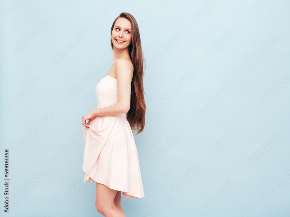 Portrait of young winsome woman in romantic attire pretty smiling on blue background. Slim female in pure pink dress posing in studio. Cheerful model. Isolated. Long hair Portrait of young winsome woman in romantic attire pretty smiling on blue background. Slim female in pure pink dress posing in studio. Cheerful model. Isolated. Long hair