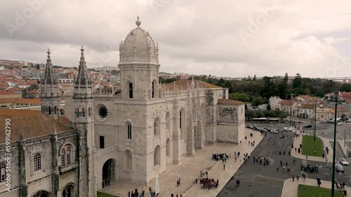 Astounding Gothic Style Of Jeronimos Monastery With Tourists Outside The Building On A Cloudy Day In Belem, Lisbon, Portugal. aerial photo