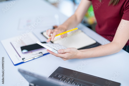 Closing of businessman or accountant hand holding pencil working on calculator to calculate business data accounting documents and a laptop computer at the office business idea