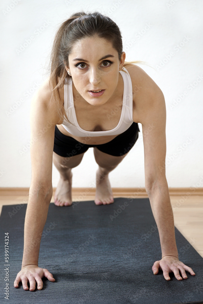 Obraz premium Slim athletic woman doing push-ups as training and exercise on sports mat